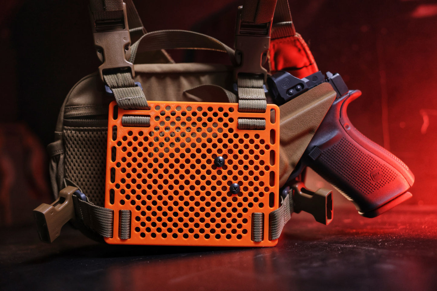 Orange tactical mounting plate on bino case with a sidearm holstered